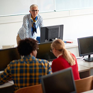 teacher in classroom with college students at computers